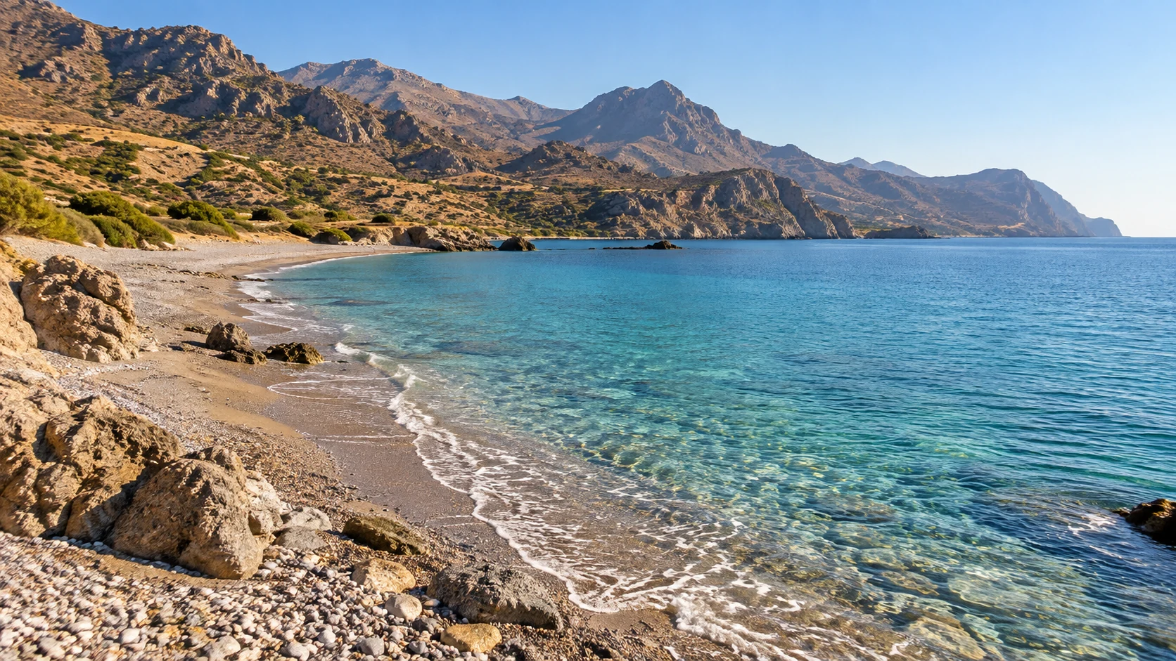 Rocky coastal cove with clear water and rugged mountains in Crete